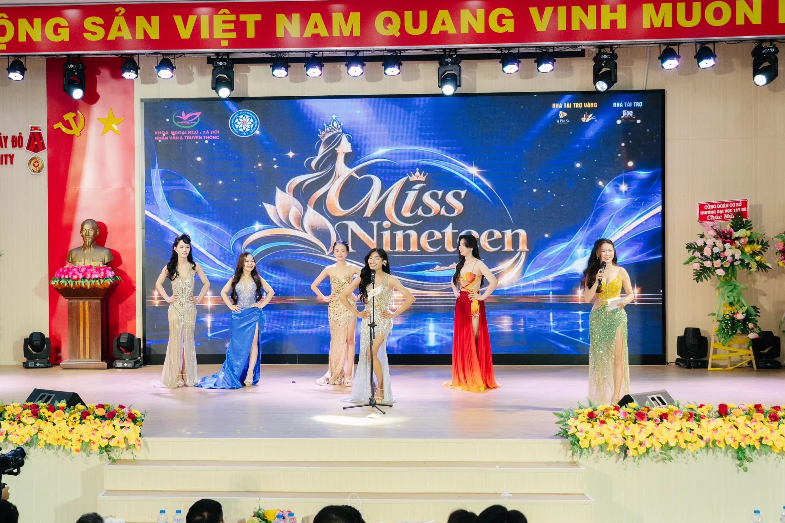 Nhiều người tham gia đứng trên sân khấu với các micro được bố trí phía trước