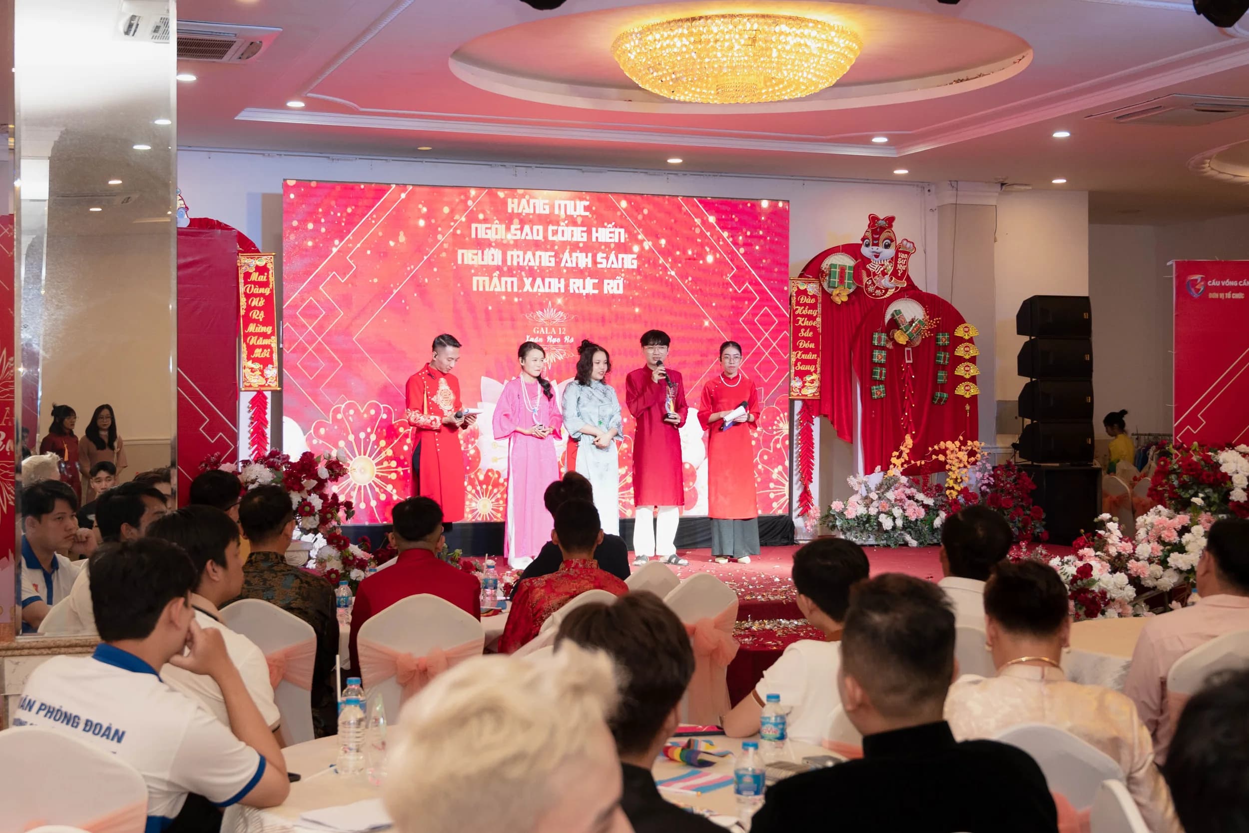 Quang cảnh buổi lễ trong hội trường với màn hình lớn và nhiều khách tham dự ngồi phía dưới hướng lên sân khấu.